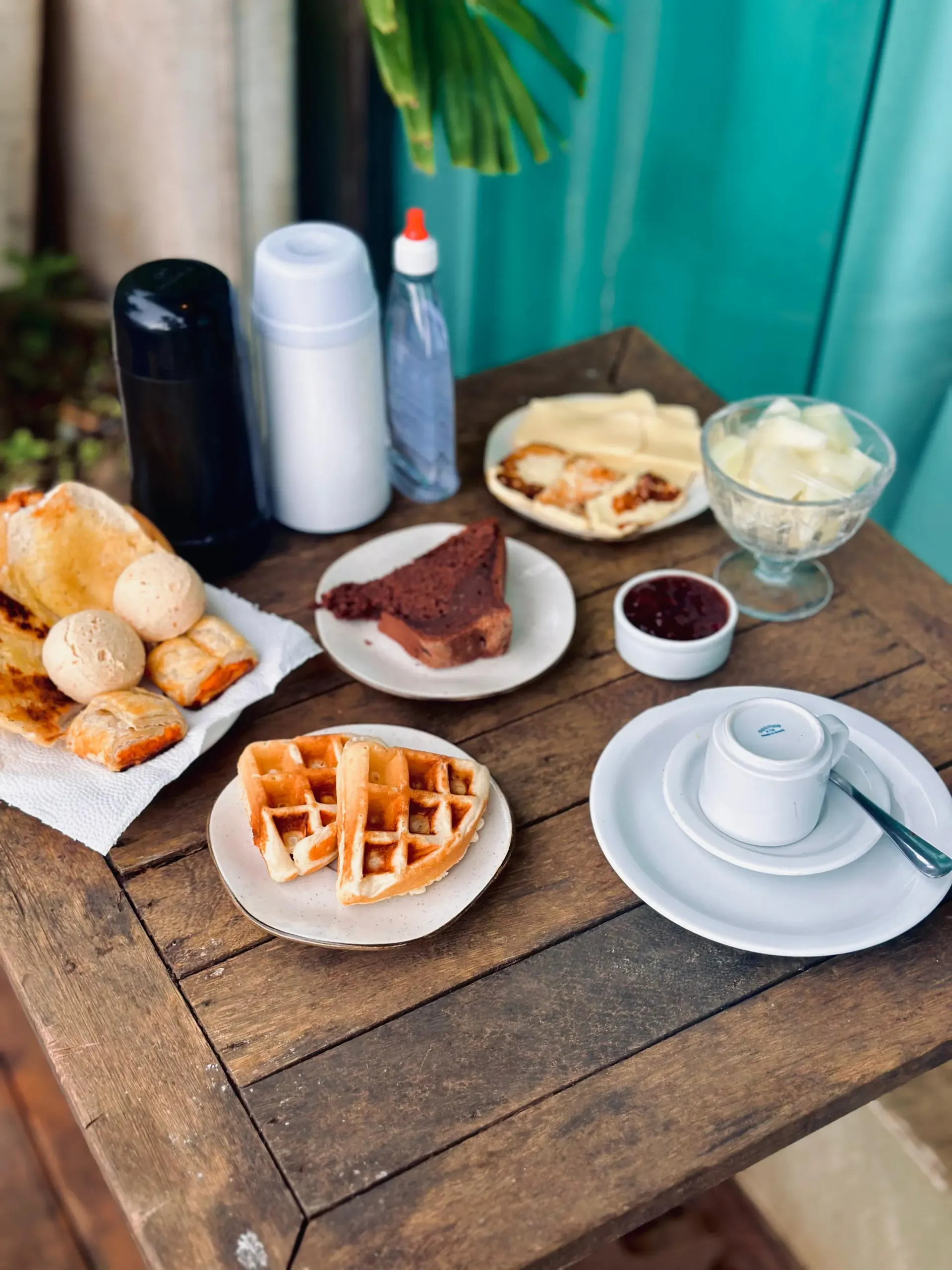 Uma mesa de madeira coberta com pratos de comida e uma xícara de café. Pousada Golfinho Fernando de Noronha