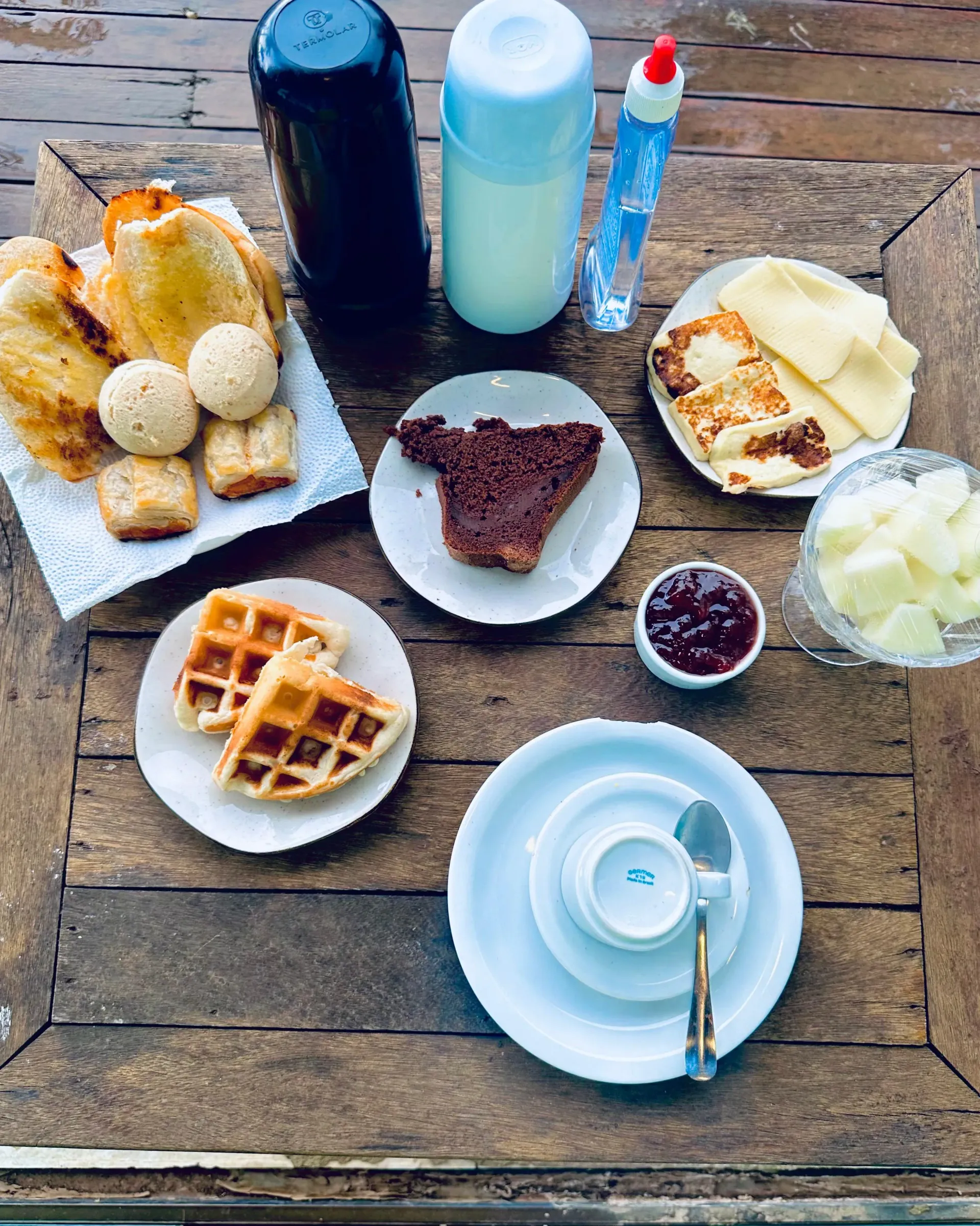 Uma mesa de madeira coberta com pratos de comida e uma garrafa de leite. Pousada Golfinho Fernando de Noronha