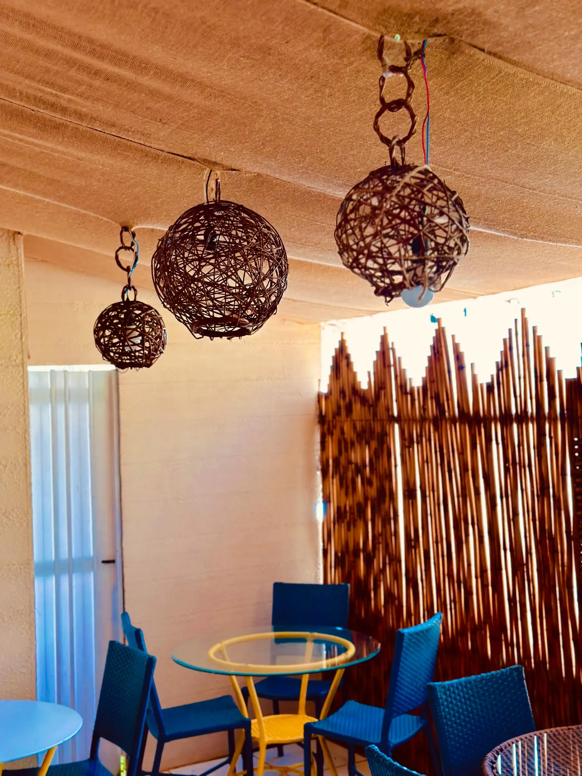 Uma sala com mesas e cadeiras e algumas lâmpadas penduradas no teto Pousada Golfinho Fernando de Noronha