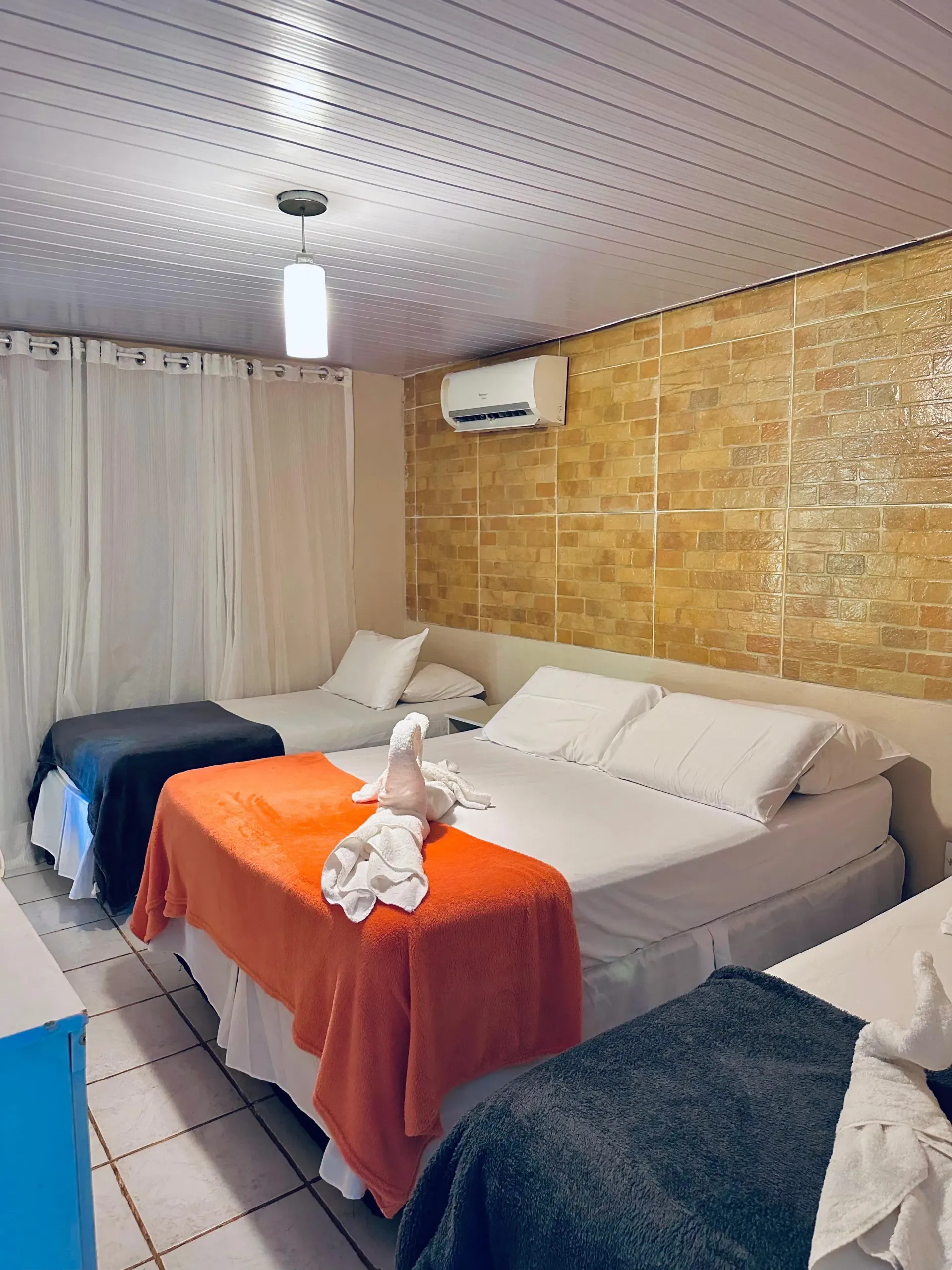 Um quarto de hotel com três camas e um ventilador de teto. Pousada Golfinho Fernando de Noronha