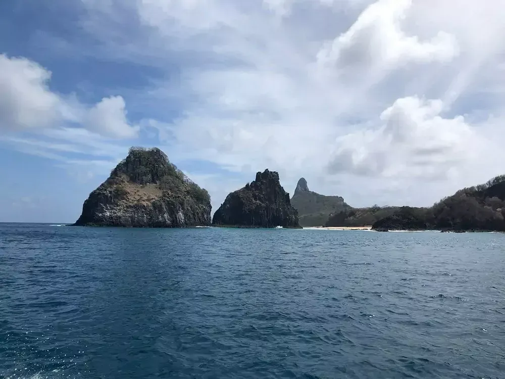 Um grande corpo de água com uma pequena ilha à distância Pousada Golfinho Fernando de Noronha