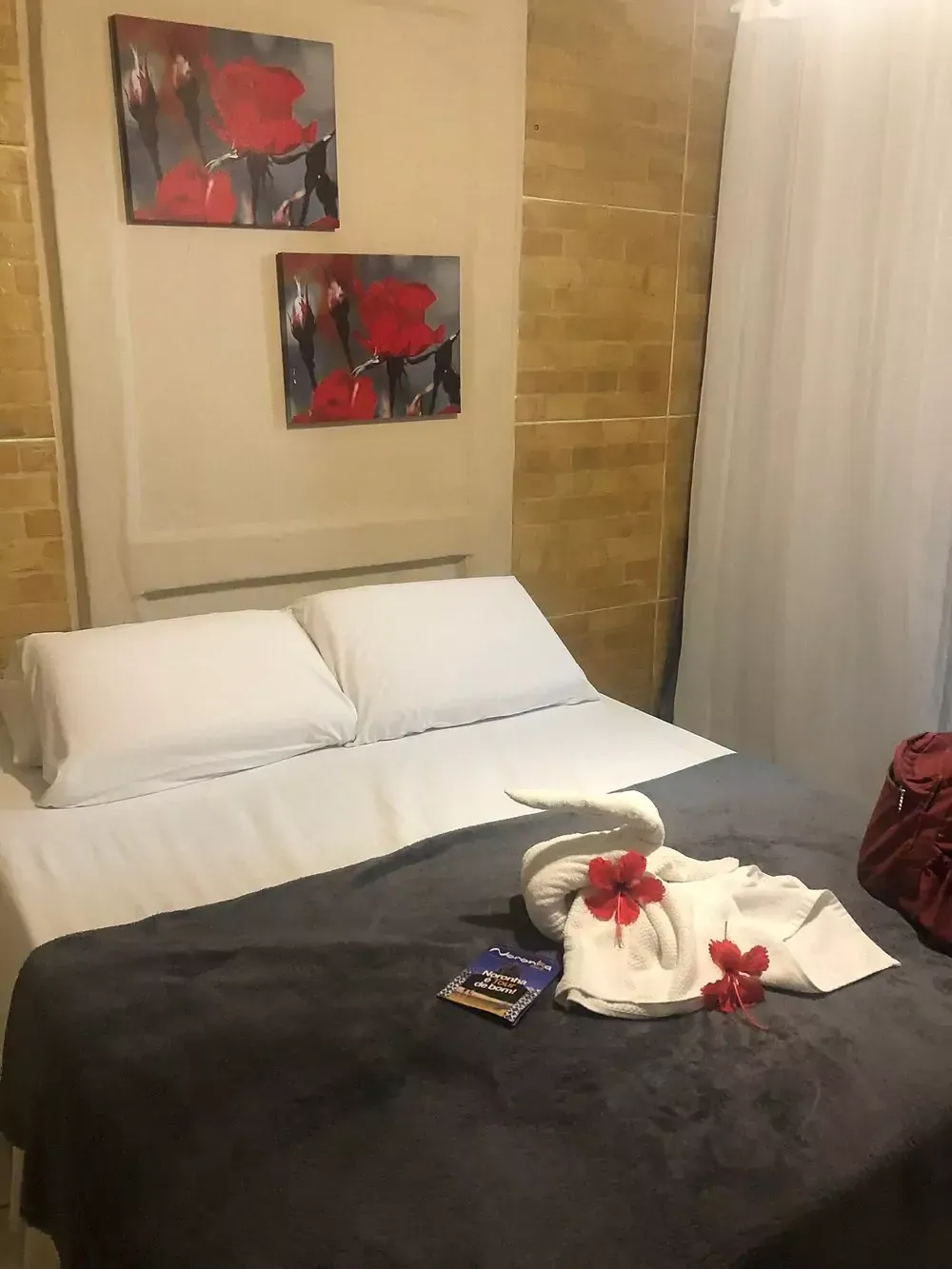 Há duas pinturas na parede acima da cama. Pousada Golfinho Fernando de Noronha