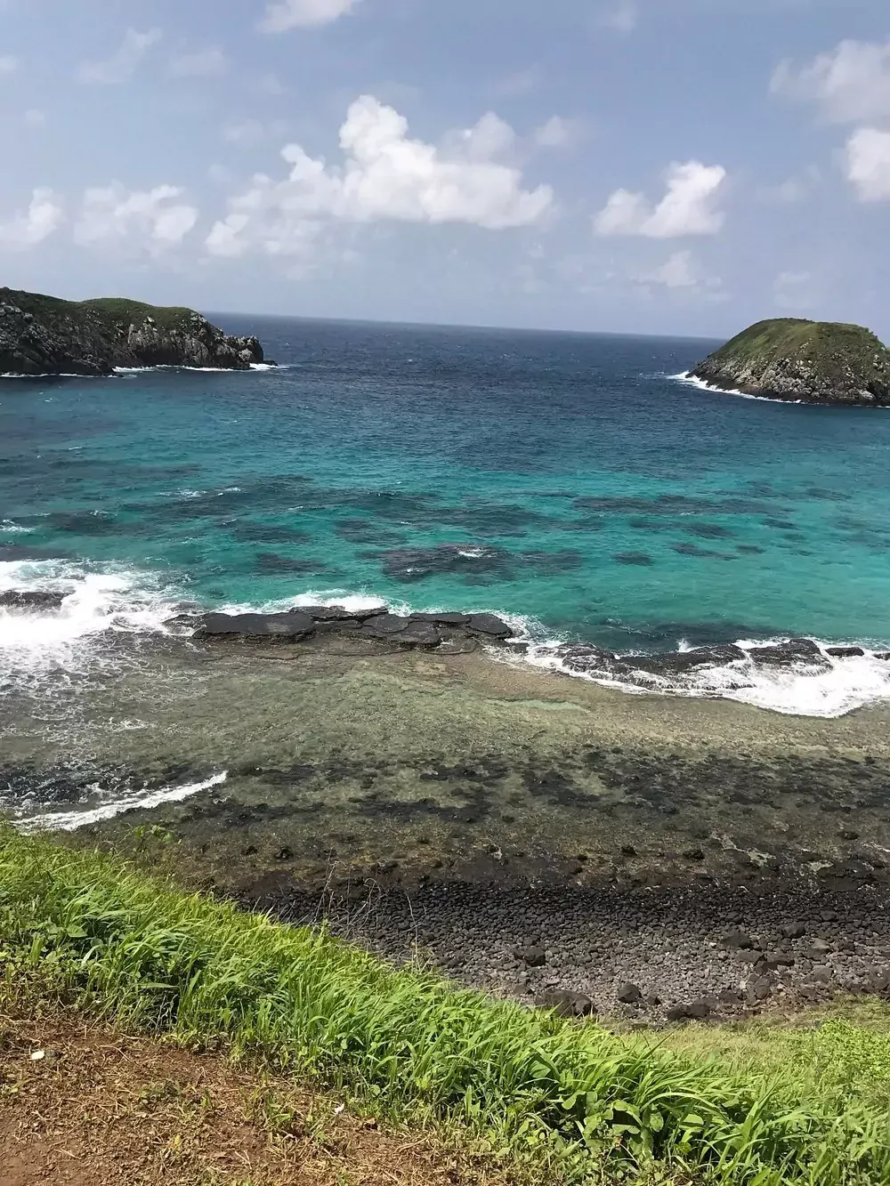Uma vista do oceano de um penhasco em um dia ensolarado. Pousada Golfinho Fernando de Noronha