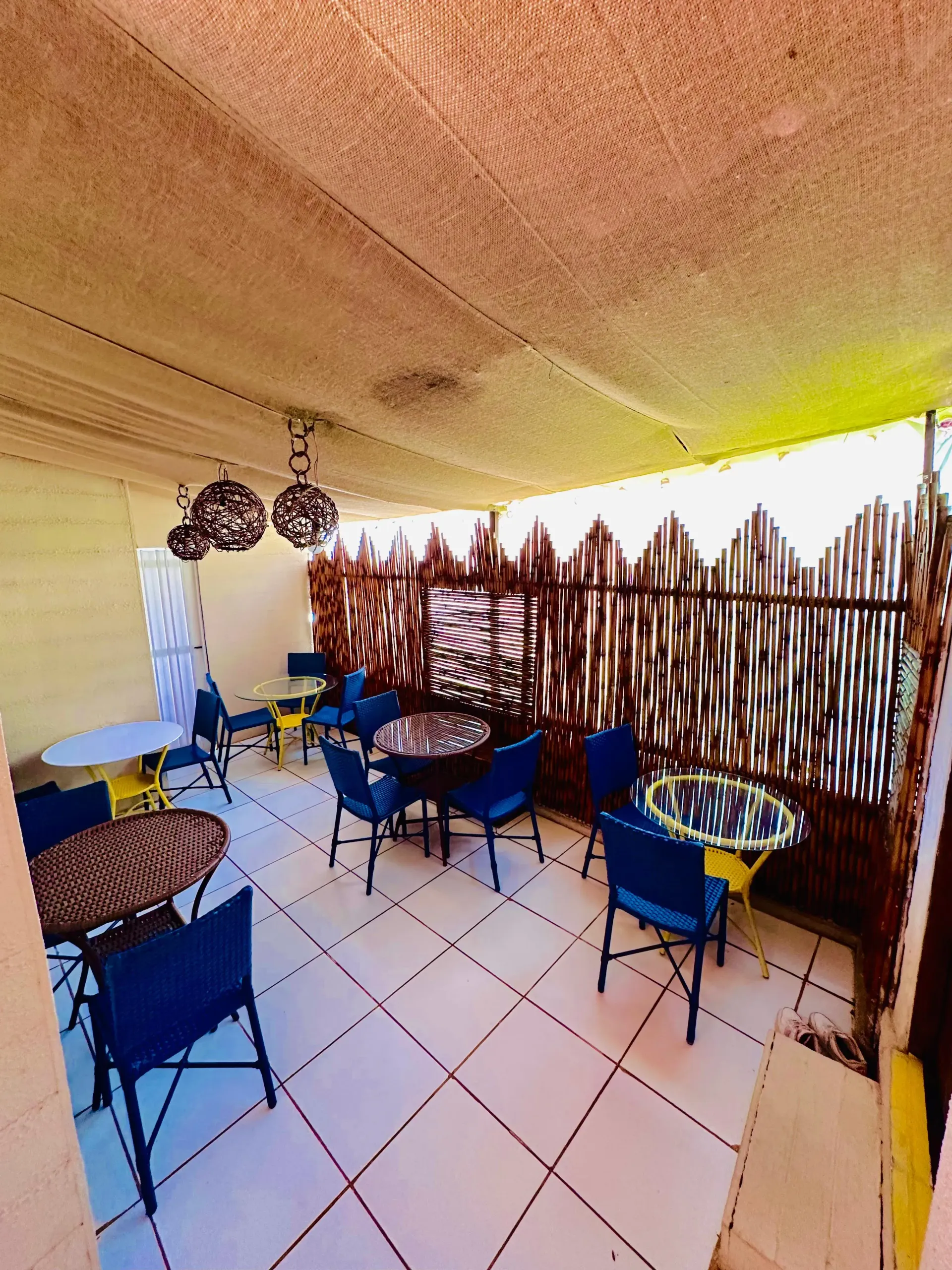 Um pátio com mesas e cadeiras sob um dossel. Pousada Golfinho Fernando de Noronha