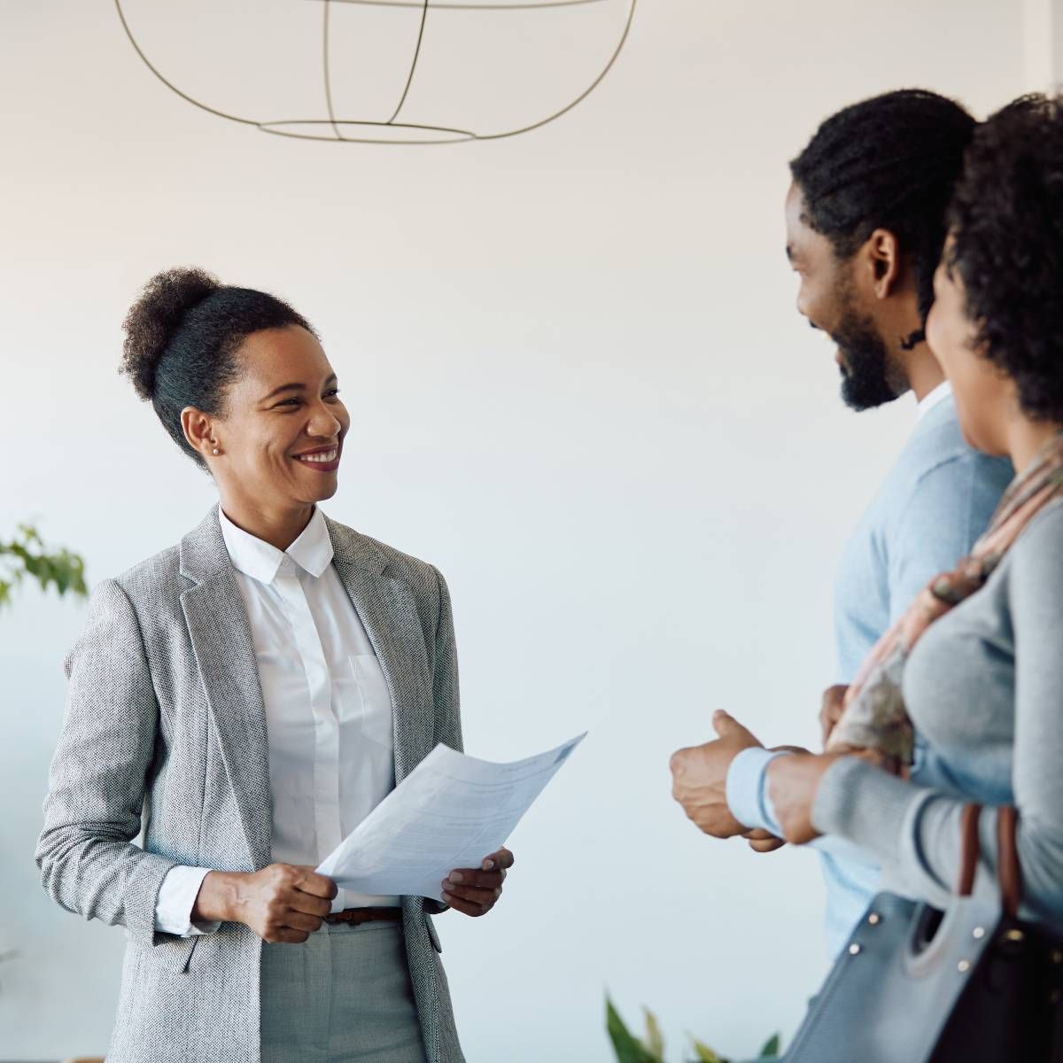 A woman is holding a piece of paper and smiling while talking to two men.