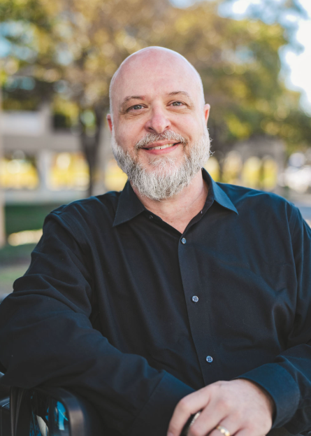 A bald man with a beard wearing a black shirt