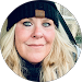 A woman wearing a black hat and scarf is smiling in a circle.