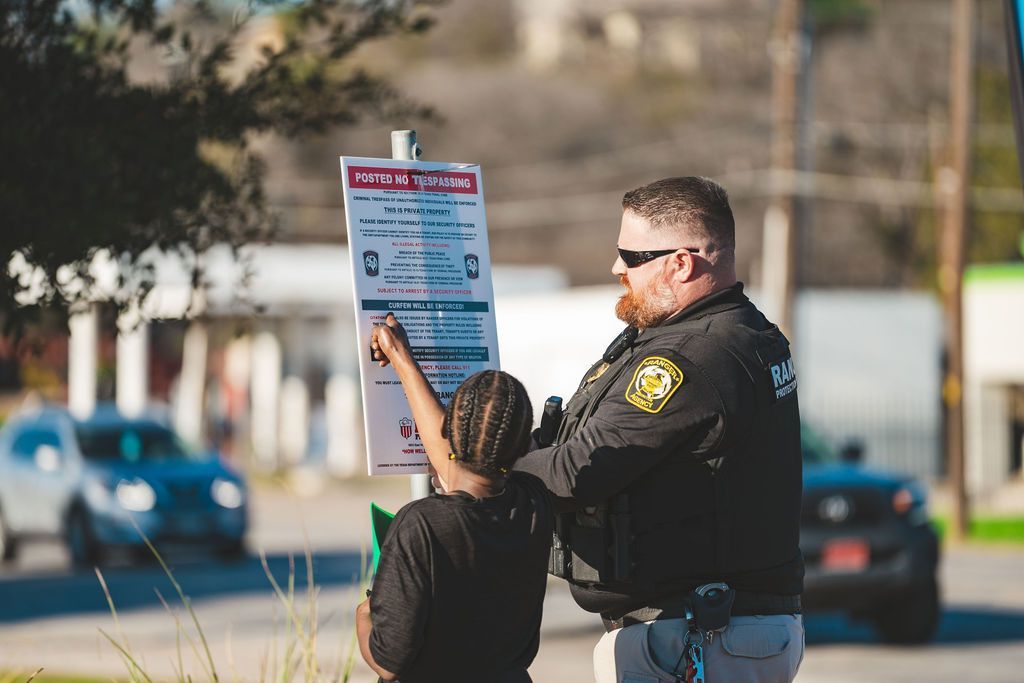 An officer is talking to a lady who is pointing at a sign