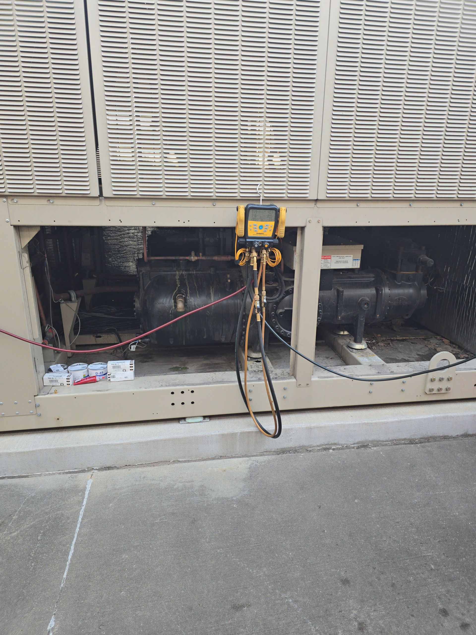 American Air Services, LLC - HVAC unit with gauges attached, likely for maintenance. Exterior view.