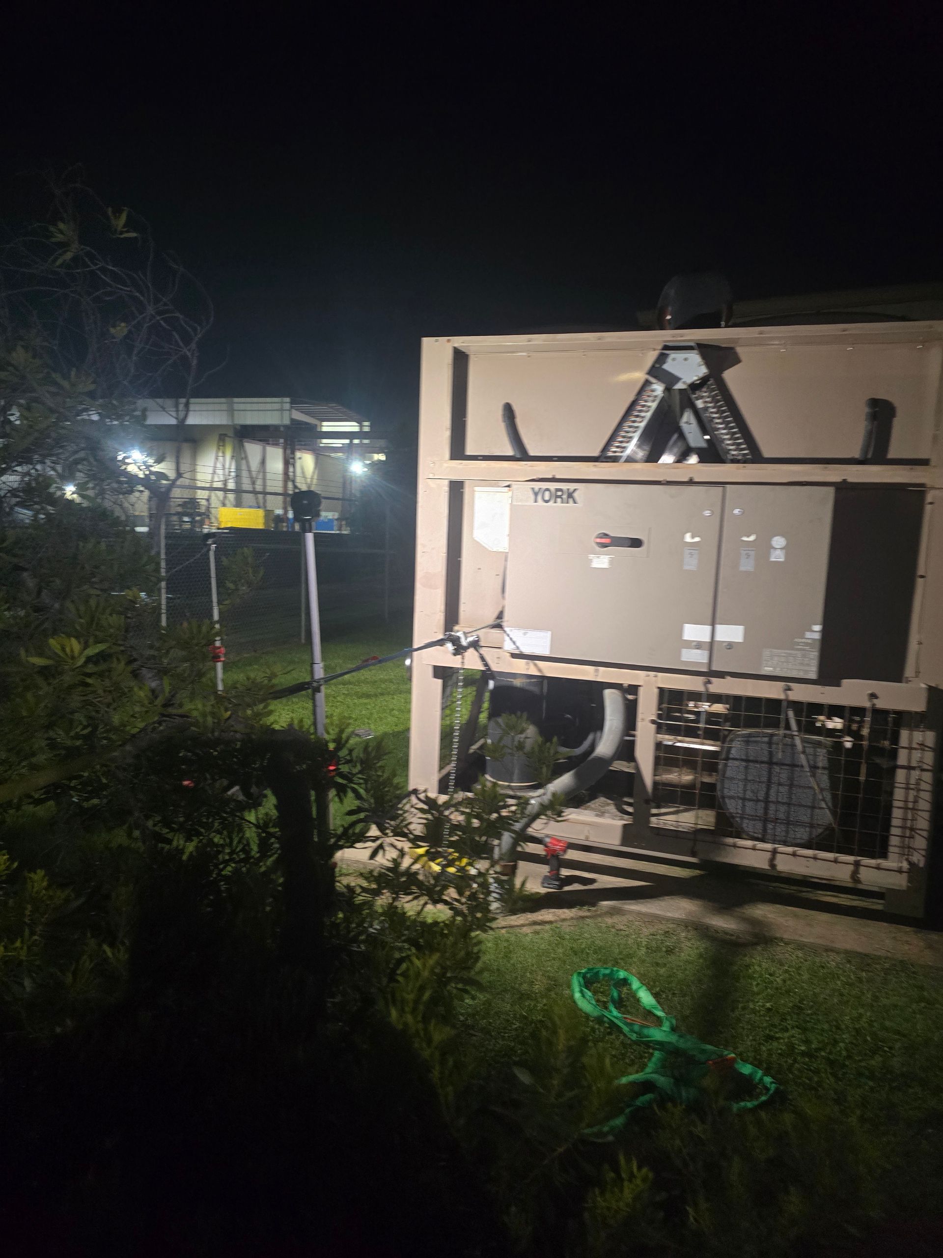 American Air Services, LLC - A large, open-sided generator in a yard at night, with nearby utility.