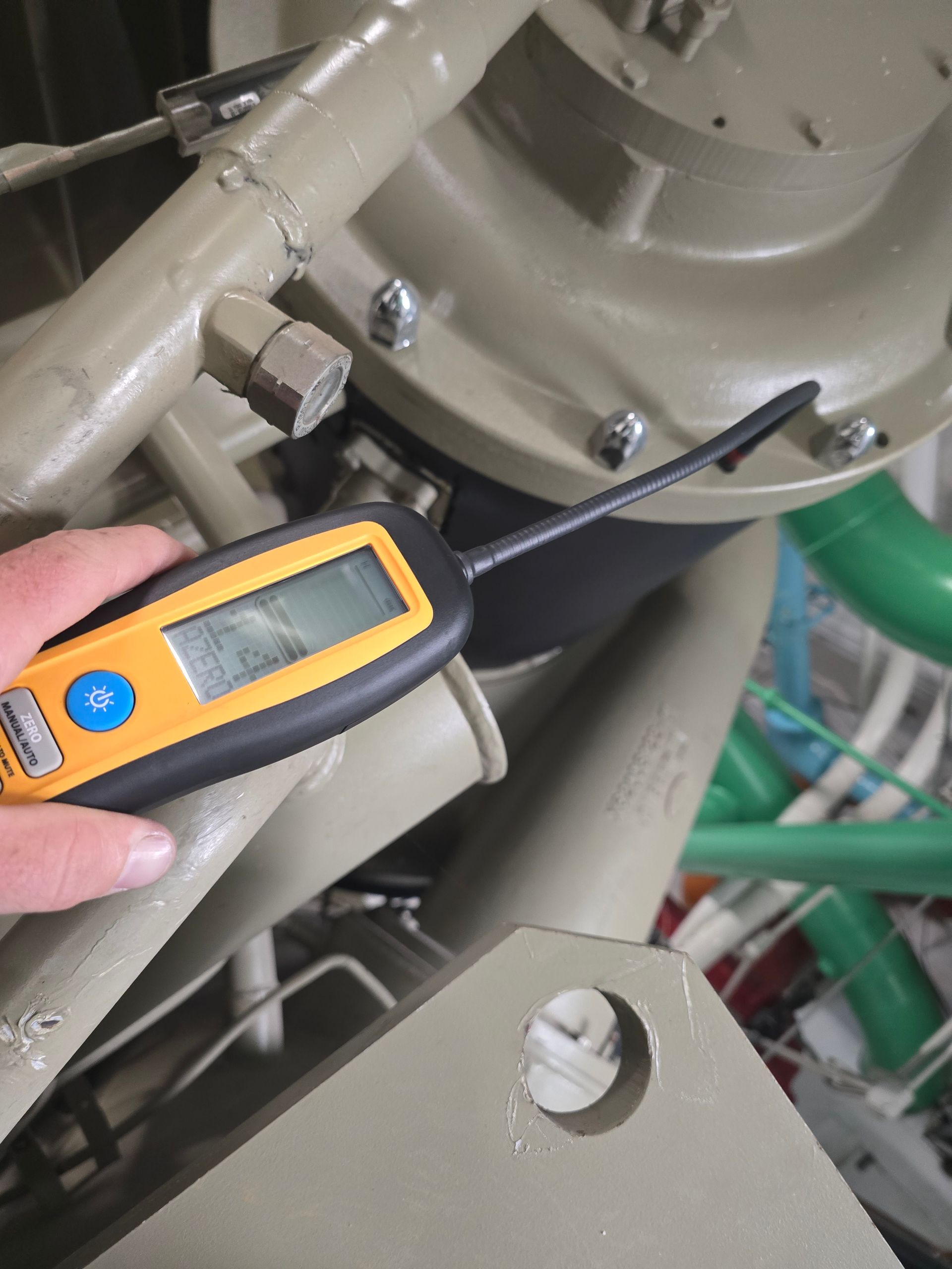 American Air Services, LLC - Hand holding a digital thermometer near a large, tan industrial component with pipes.