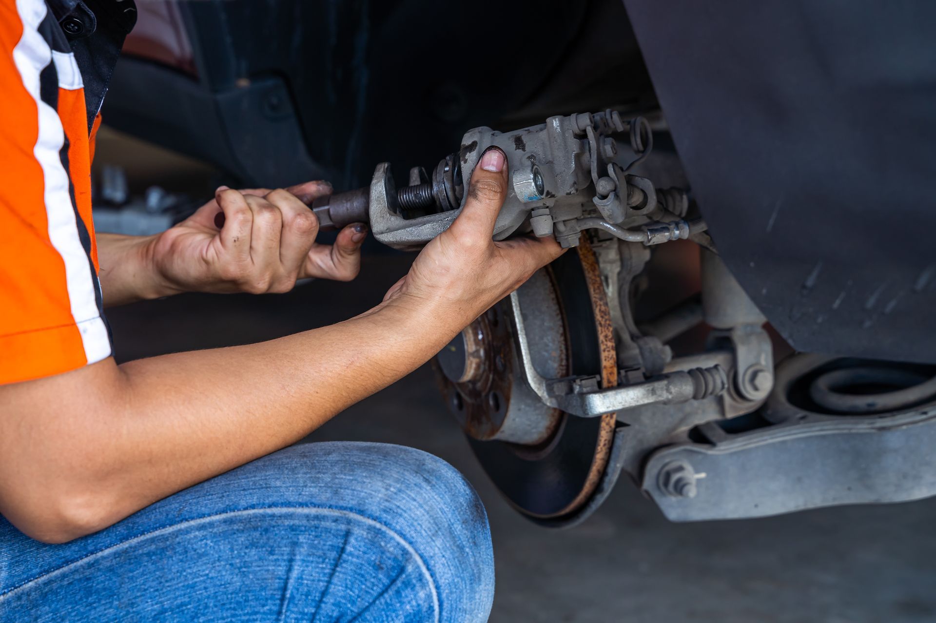 Mechanic replacing car brake, using a tool. The setting is a garage or repair shop. | Southgate Automotive