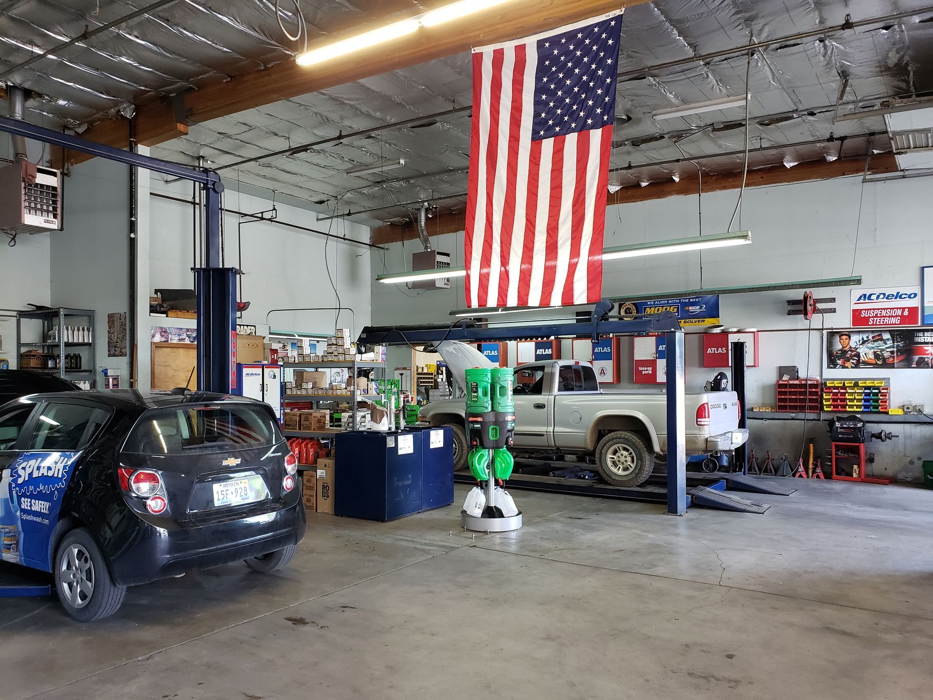 Auto repair shop interior with American flag, two vehicles on lifts, tools, and equipment. | Southgate Automotive