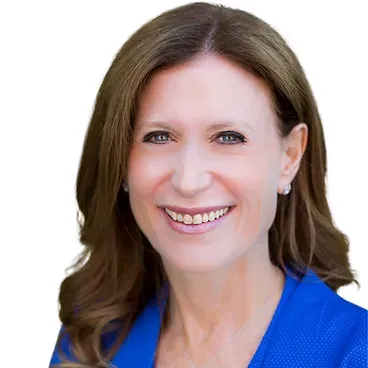 A woman in a blue jacket is smiling for the camera.