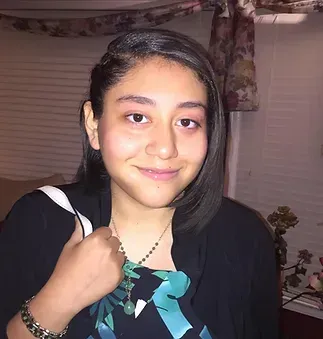 A young woman wearing a black jacket and a necklace is smiling for the camera.
