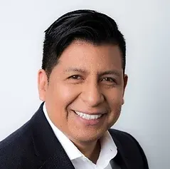 A man in a suit and white shirt is smiling for the camera.