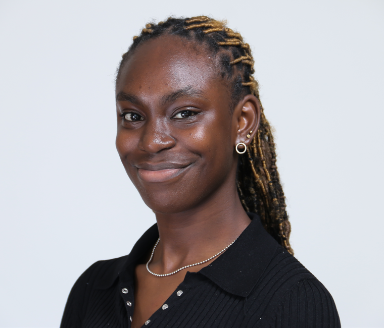 A woman wearing a black shirt and earrings is smiling for the camera.