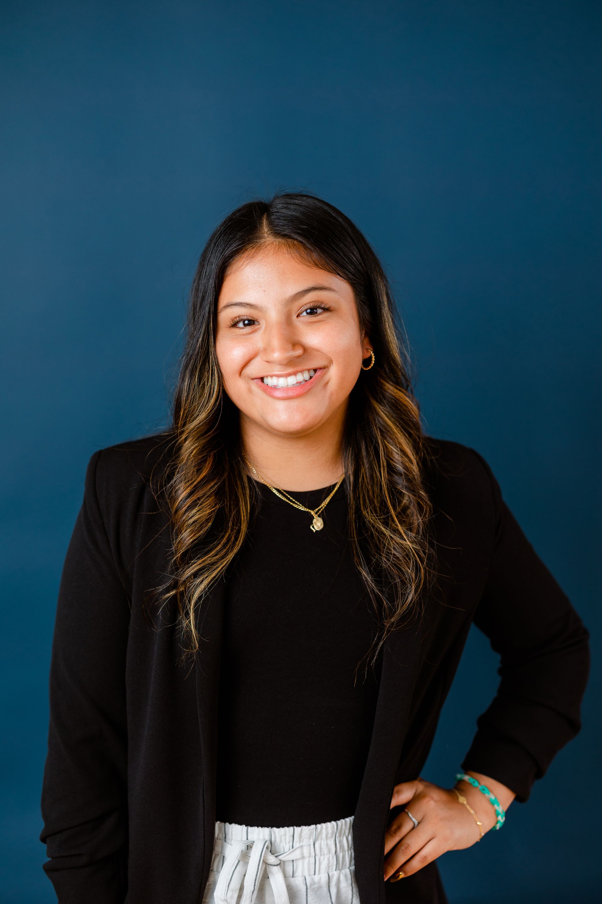 A woman is standing in front of a blue wall with her hands on her hips.