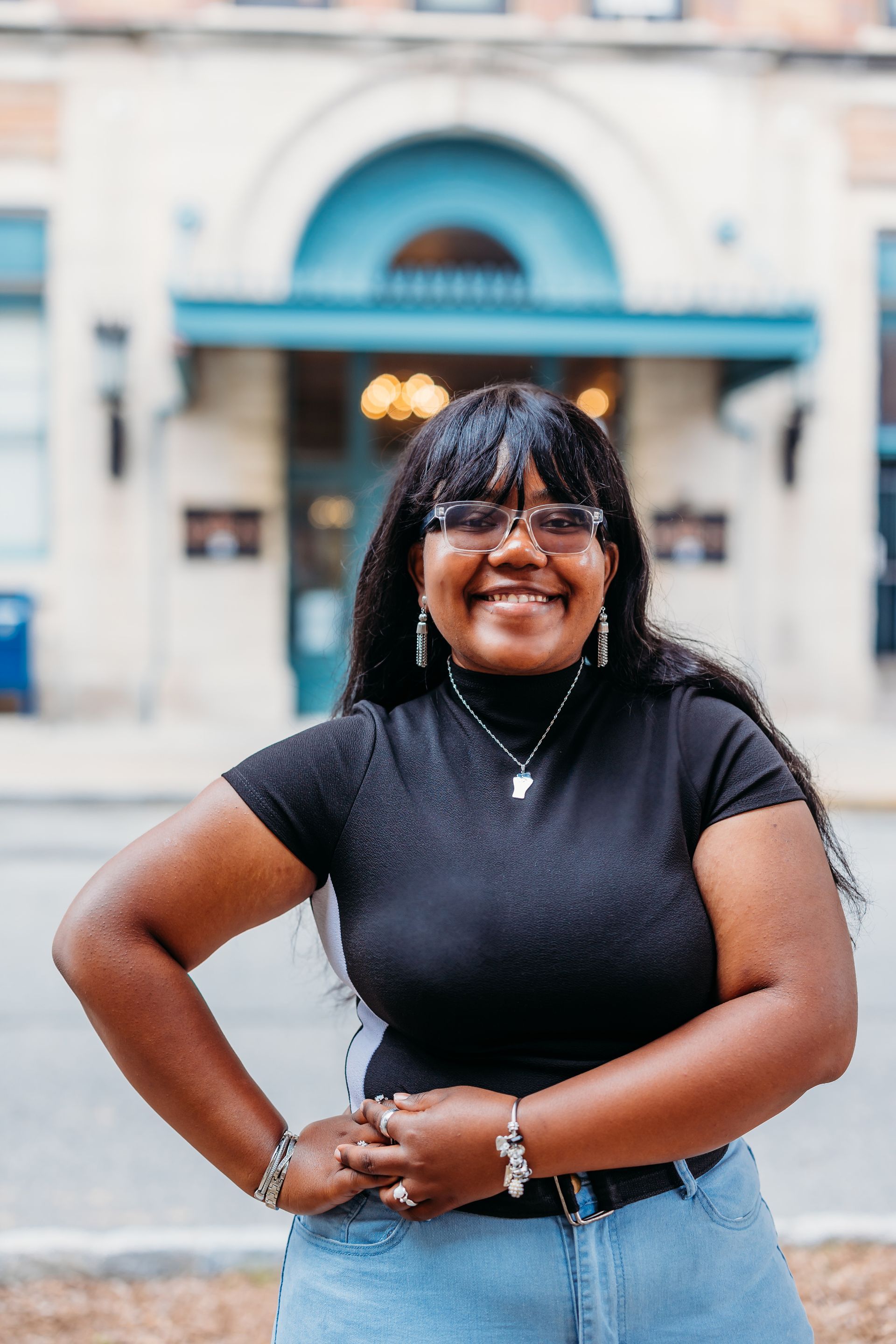 A woman is standing in front of a building with her hands on her hips.