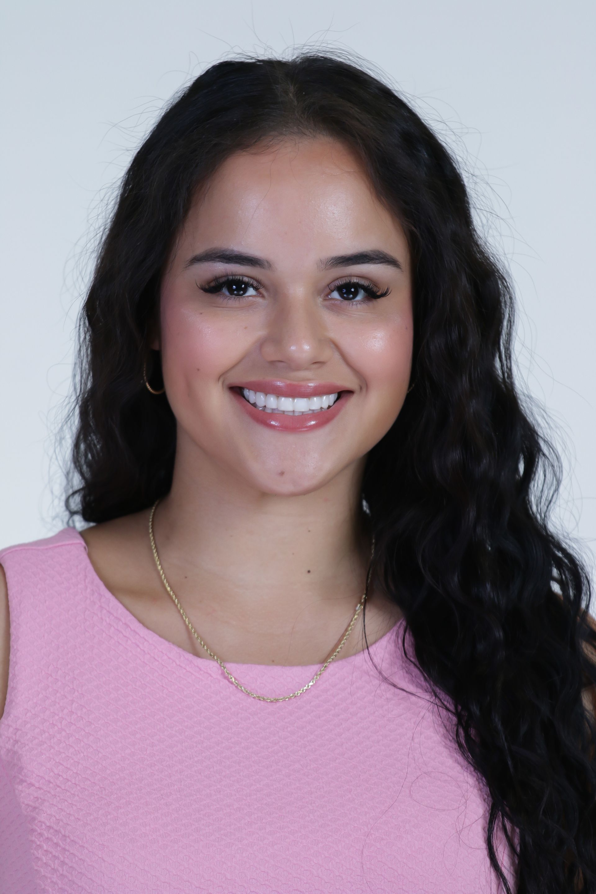 A woman in a pink dress is smiling for the camera.
