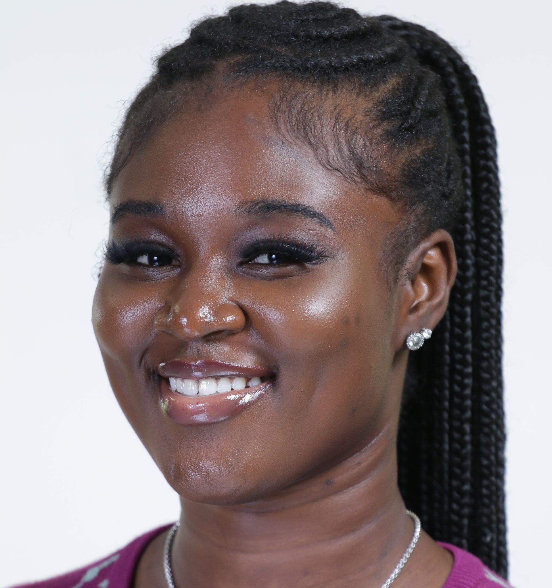 A woman with braids and earrings smiles for the camera