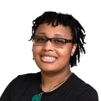 A woman wearing glasses and a black shirt is smiling for the camera.