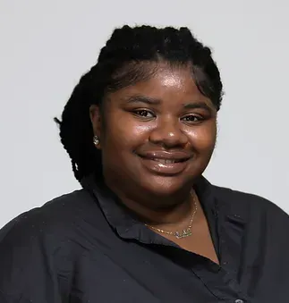 A woman wearing a black shirt and a gold necklace is smiling for the camera.