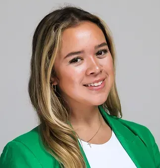 A woman wearing a green jacket and a white shirt is smiling for the camera.