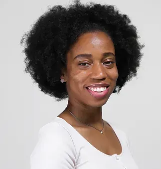 A woman with afro hair is smiling and wearing a white shirt.