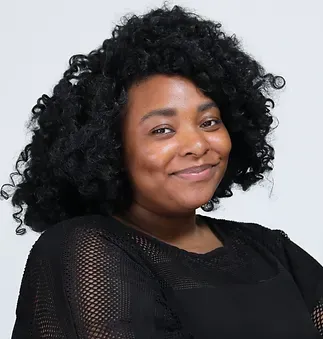A woman with curly hair is wearing a black shirt and smiling.