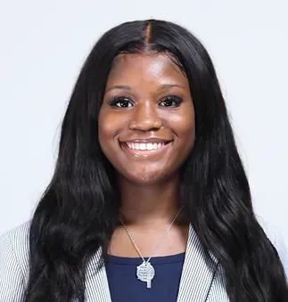 A woman with long hair and a necklace is smiling for the camera.