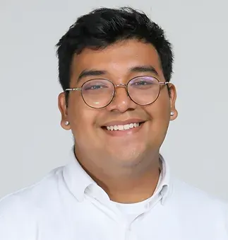 A man wearing glasses and a white shirt is smiling.