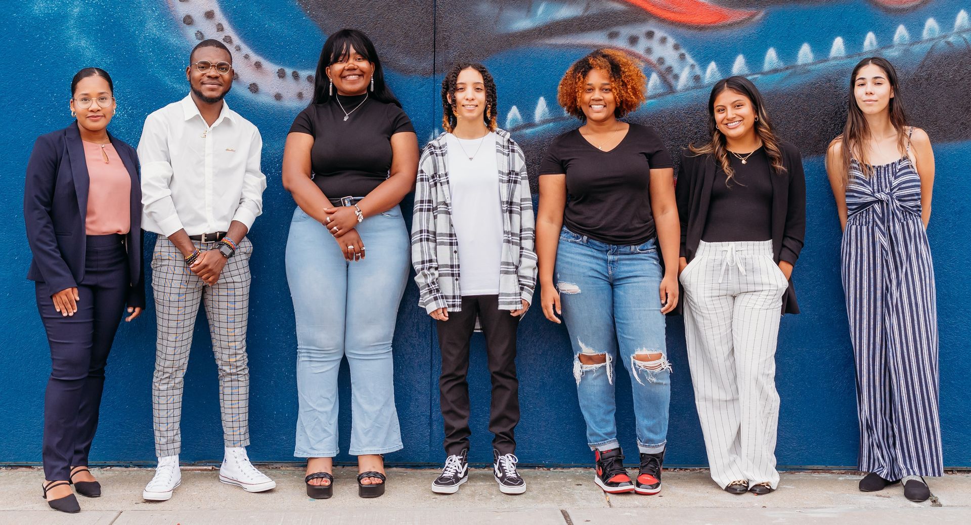 A group of people are standing in front of a blue wall.