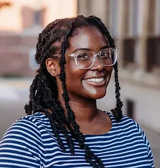 A woman wearing glasses and a striped shirt is smiling.