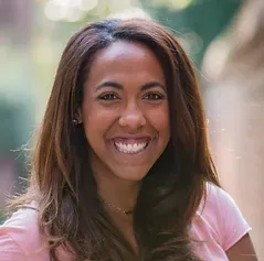 A woman in a pink shirt is smiling for the camera.