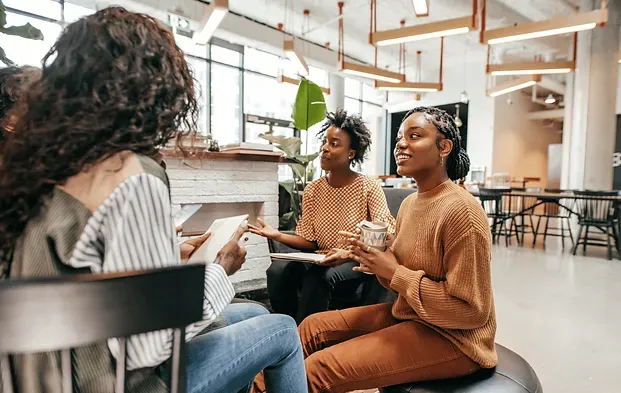 A group of women are sitting in a circle talking to each other.