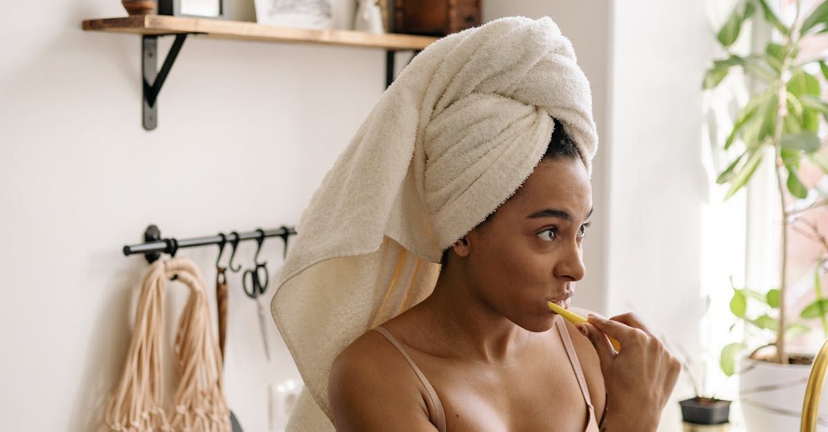 A woman with a towel wrapped around her head is brushing her teeth.