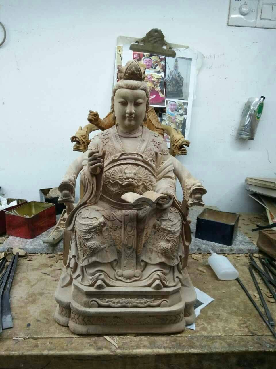 工作坊的工作台上放著一尊陶土製成的坐姿神像,旁邊擺放著工具和材料。