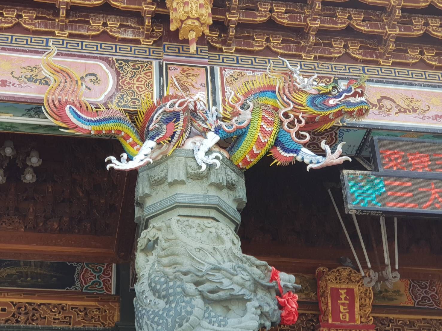 華麗寺廟屋頂上的石柱頂端,矗立著色彩繽紛的龍形雕塑。