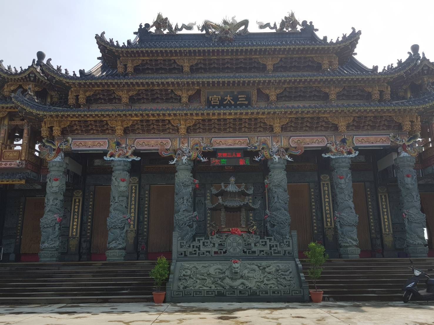 精美的中國寺廟立面,飾有雕刻精美的柱子、石階和色彩繽紛的屋頂細節。