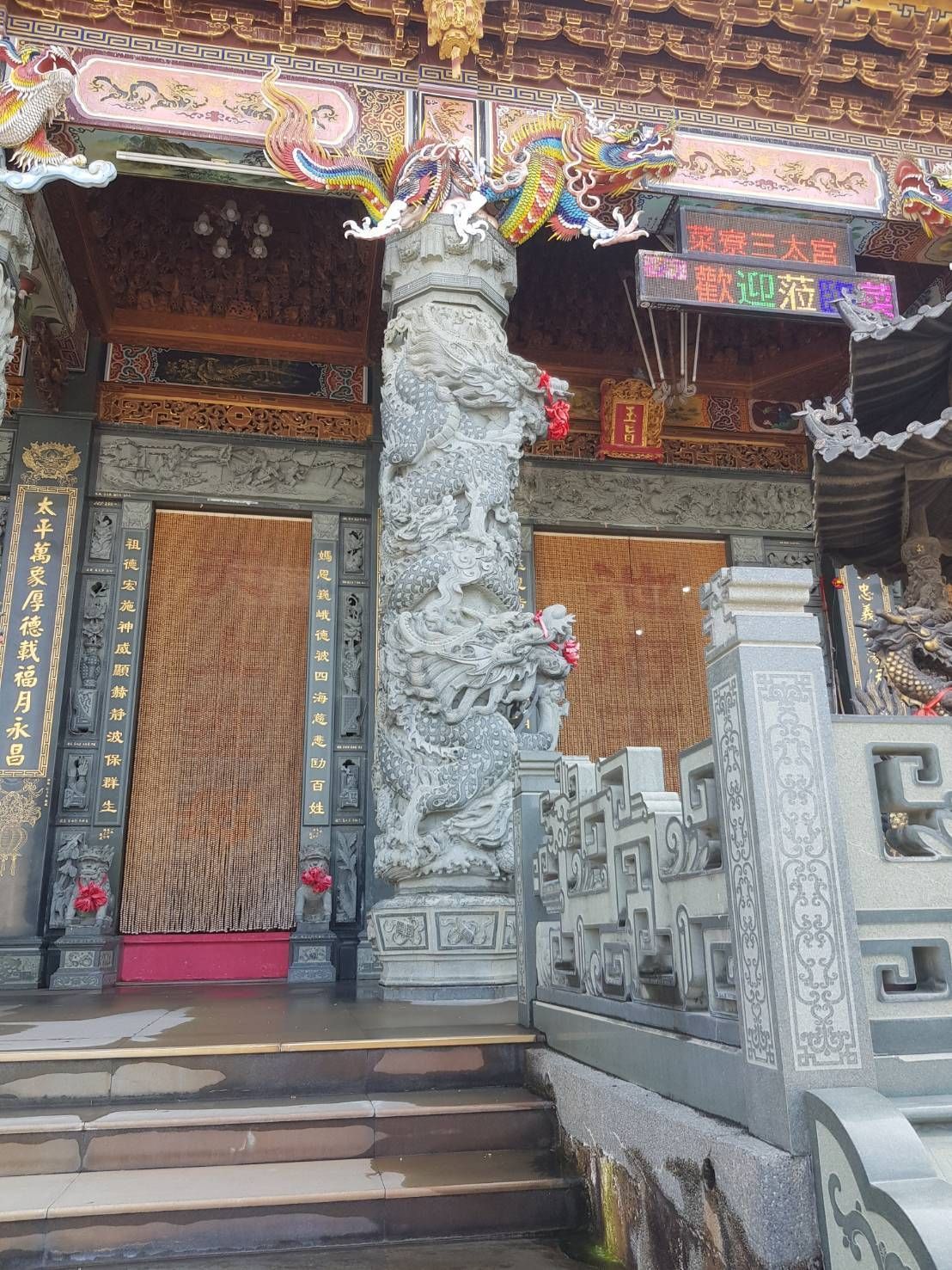 寺廟入口裝飾華麗,有雕花石柱、木門和色彩繽紛的裝飾線條。
