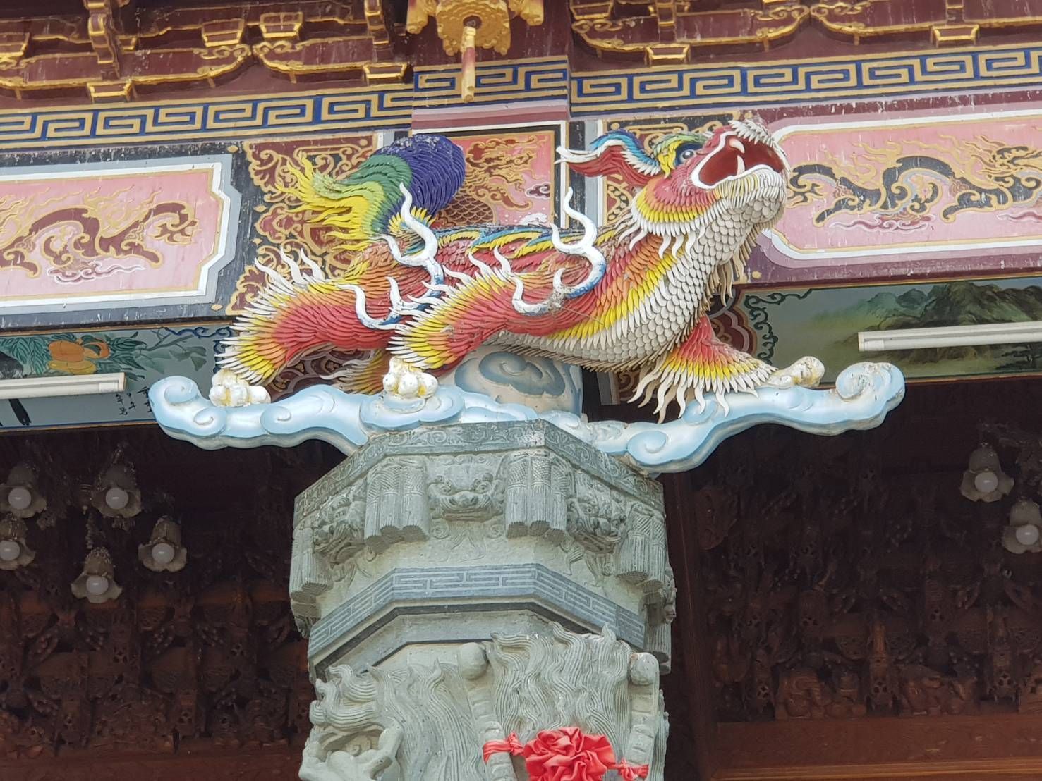色彩繽紛的龍形雕塑矗立在裝飾華麗的寺廟柱頂,下方是精美的屋簷。