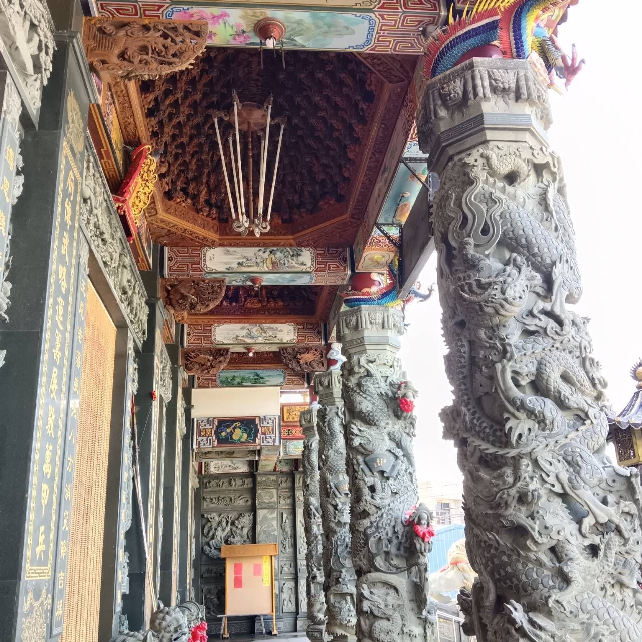 華麗的寺廟走廊,有雕刻精美的石柱、色彩繽紛的天花板裝飾和懸掛的燈籠。