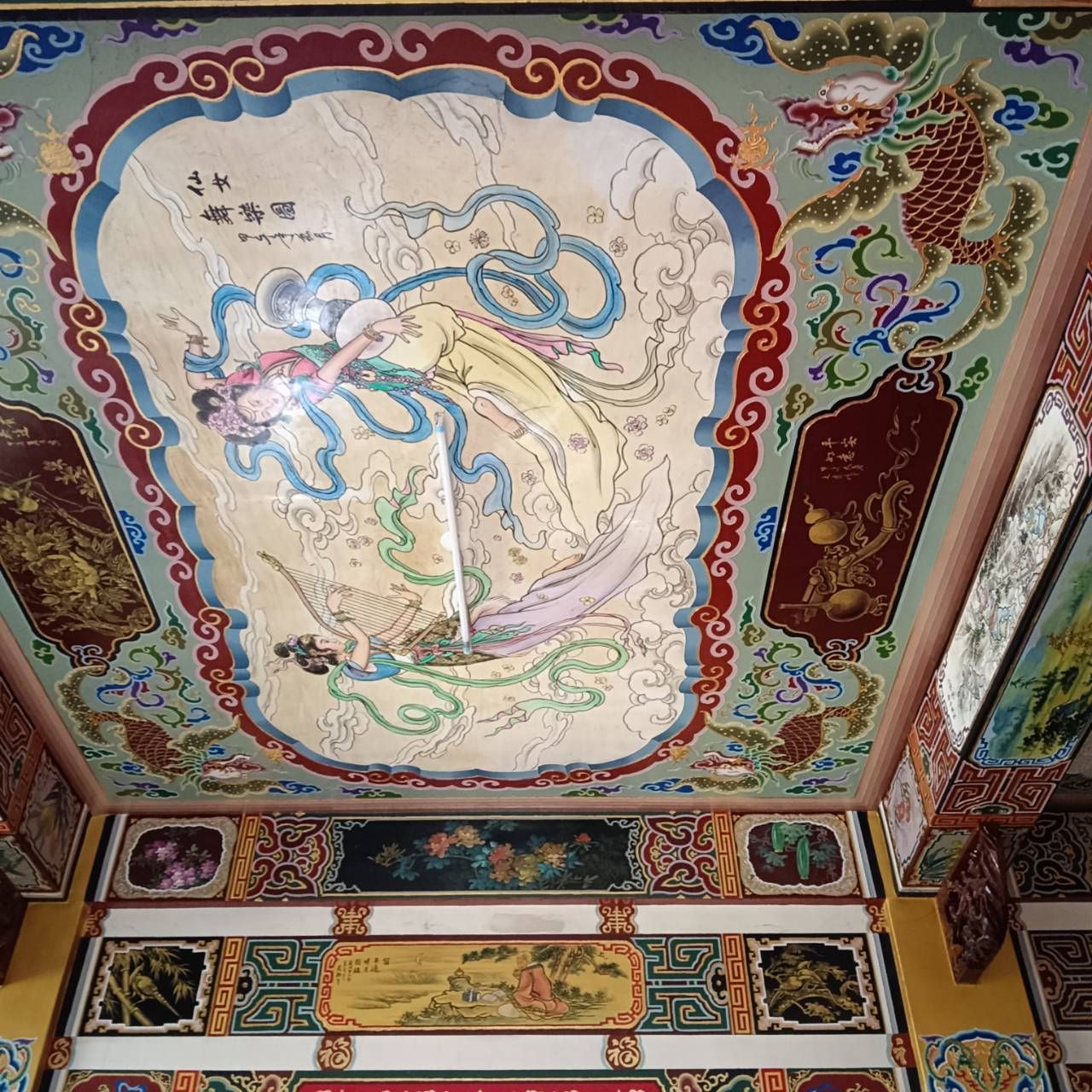色彩繽紛、裝飾華麗的寺廟天花板壁畫,繪有藍色龍紋和精美的中國書法裝飾板。