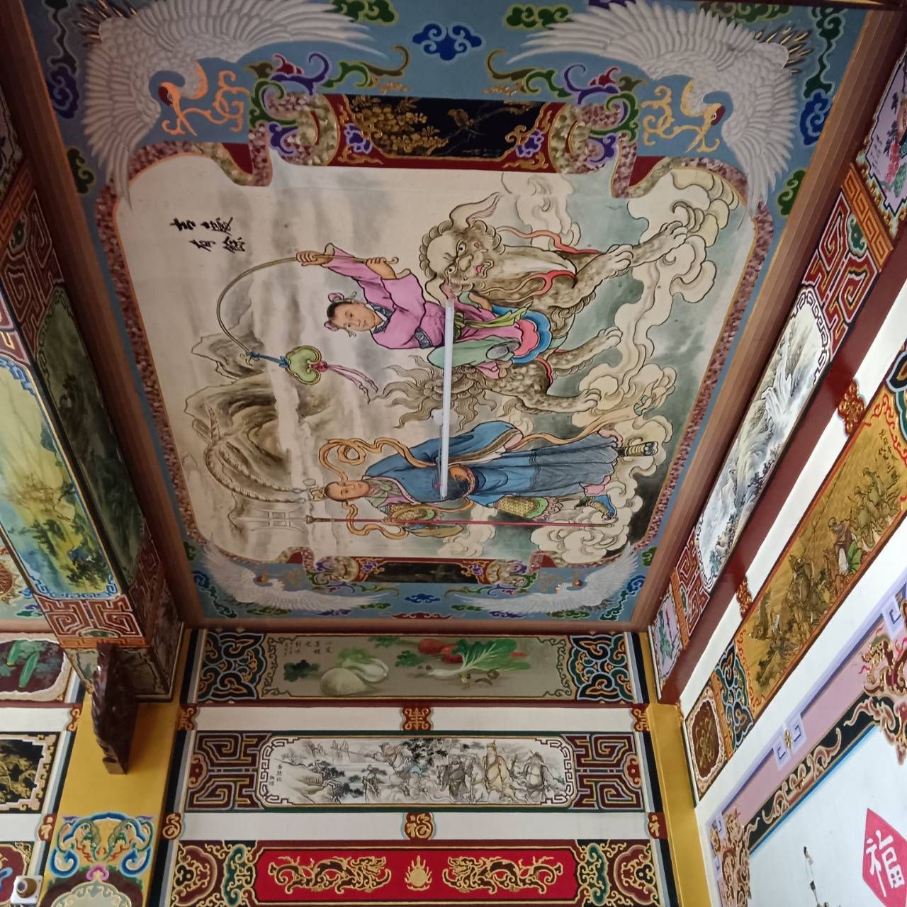 色彩繽紛的彩繪寺廟天花板,飾有華麗的壁畫、雲朵、人物和金色裝飾邊框。