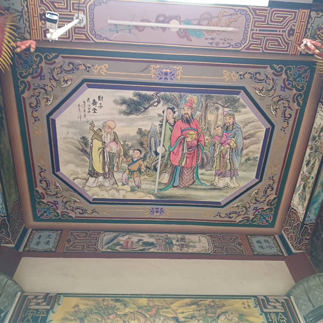 華麗的彩繪天花板嵌板,描繪了身著色彩鮮豔長袍的人物的傳統場景,四周飾以裝飾性邊框。