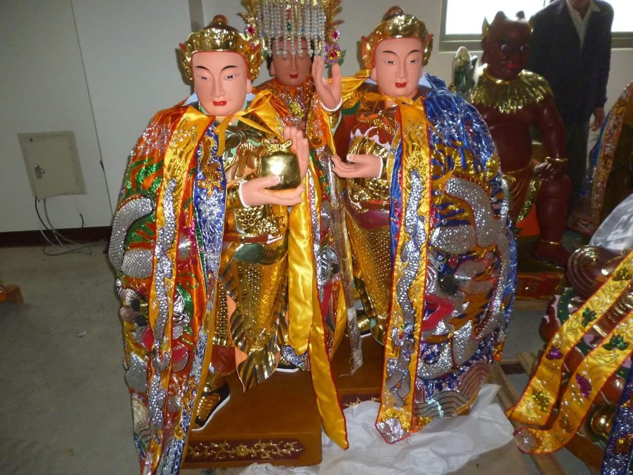 室內地板上擺放著身著金銀長袍的色彩鮮豔的祭祀雕像。