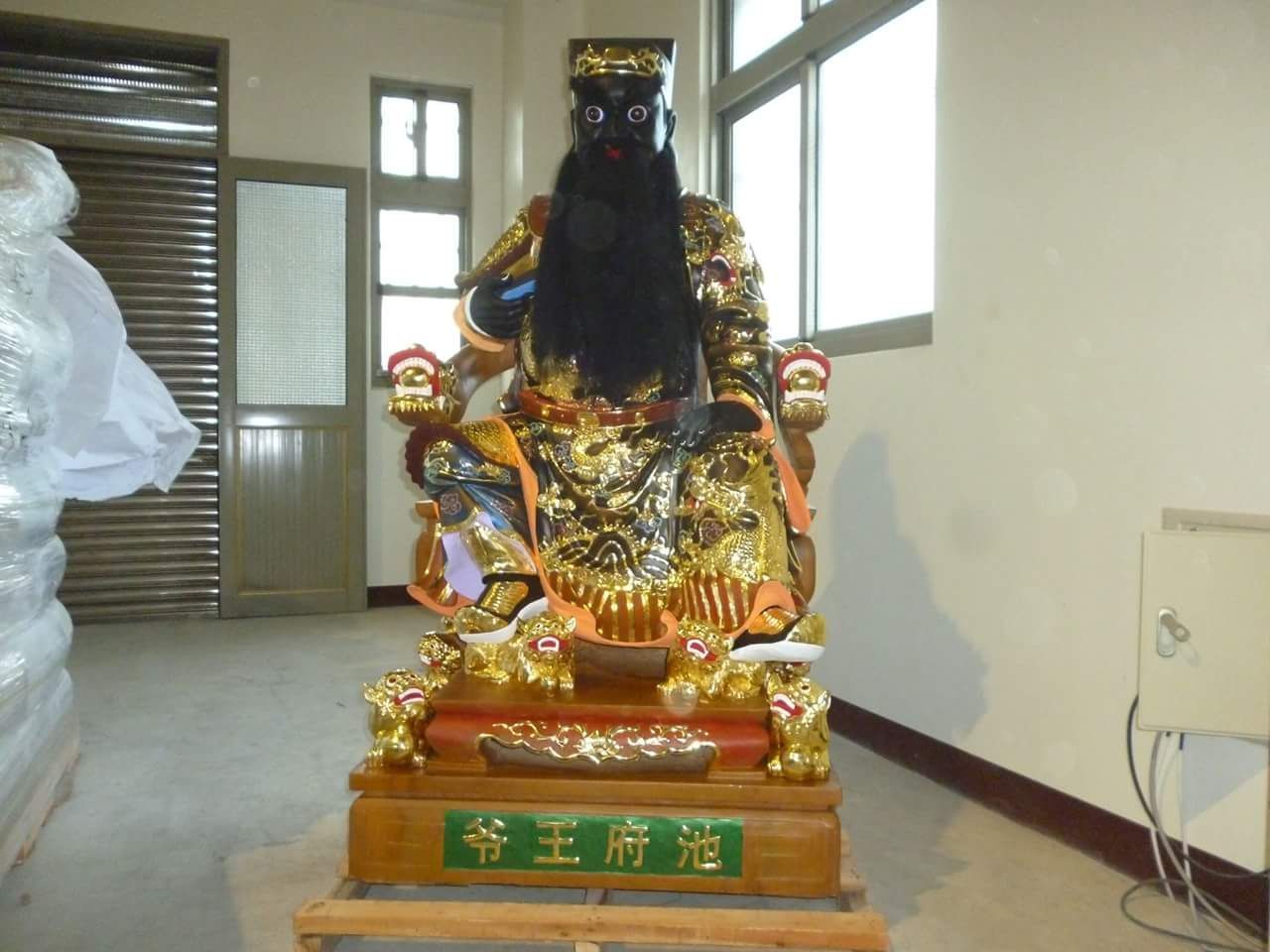 室內,黑色神像,飾以金色點綴,置於紅金相間的底座上。
