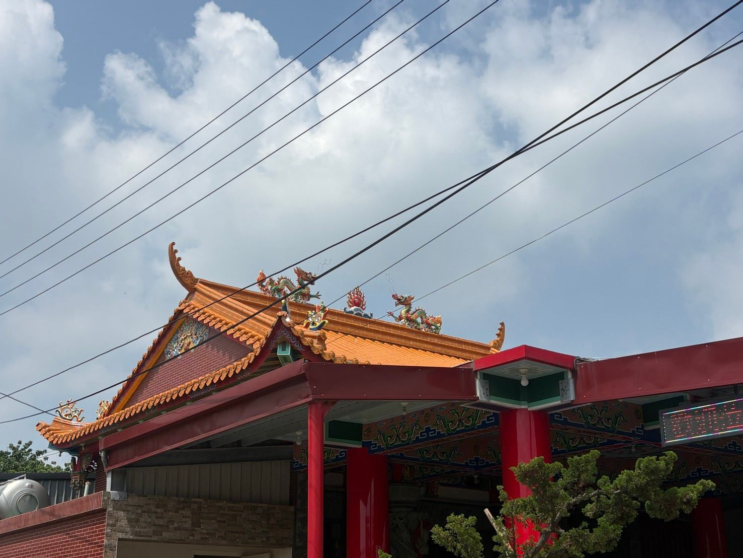 在陰雲密佈的天空下,傳統的寺廟入口,屋頂鋪著華麗的橘色瓦片。