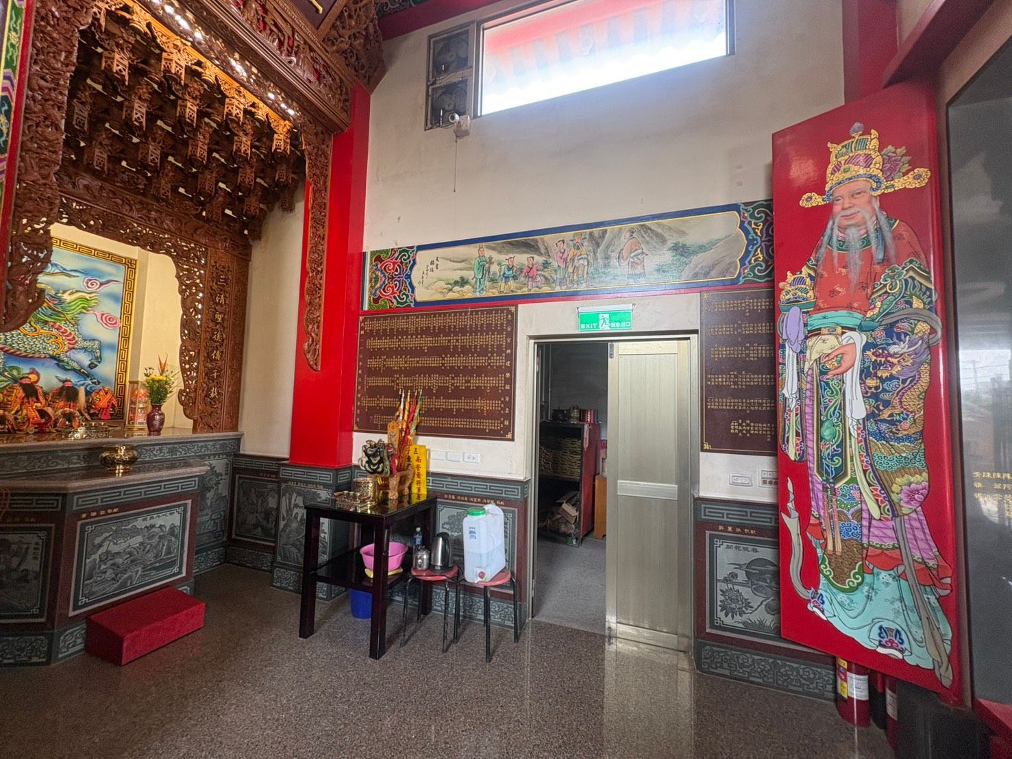 寺廟內部裝飾華麗,有紅色立柱、祭壇裝飾,以及位於發光出口標誌下的入口。